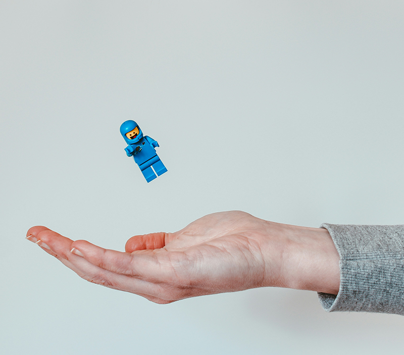 close up of hand catching a lego man in a blue suit