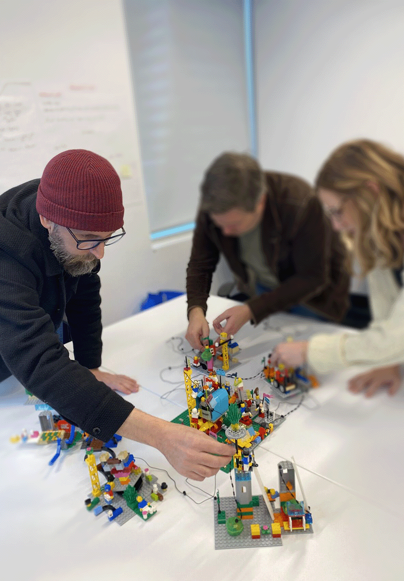 three people building with lego bricks together