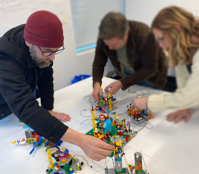 three people building with lego bricks together